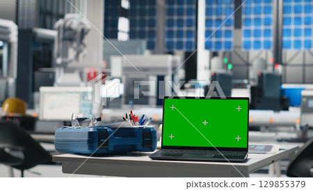 Green screen on a laptop at empty photovoltaics desk to help with green energy, used for optimizing energy supply in solar panels manufacturing plant. High tech engineering industry. Green screen on a laptop at empty photovoltaics desk to help with green energy, used for optimizing energy supply in solar panels manufacturing plant. High tech engineering industry. 129855379