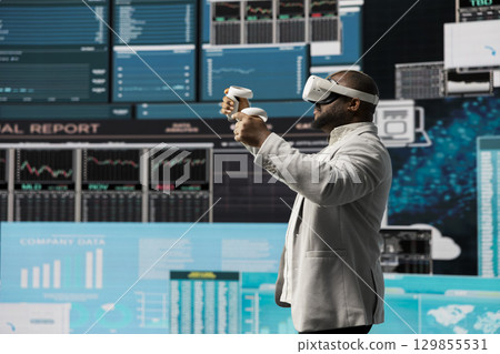 High tech startup entrepreneur using virtual reality glasses to examine KPI models, reviewing infographics and working on business productivity. Professional VR gadget simulation. High tech startup entrepreneur using virtual reality glasses to examine KPI models, reviewing infographics and working on business productivity. Professional VR gadget simulation. 129855531