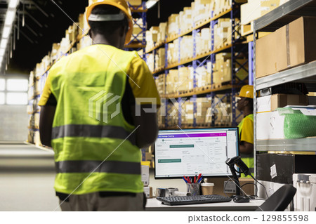 Warehouse worker focusing on supply chain logistics with tracking software, managing shipping labels for e-commerce orders. Man organizing items for shipping and ensuring inventory check. Warehouse worker focusing on supply chain logistics with tracking software, managing shipping labels for e-commerce orders. Man organizing items for shipping and ensuring inventory check. 129855598