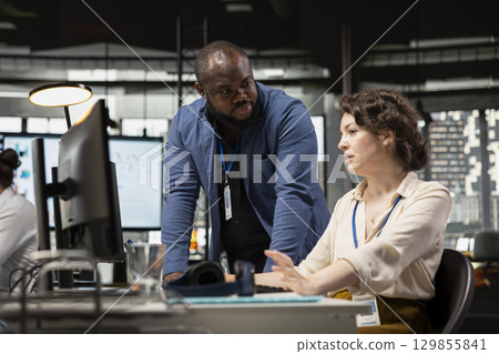 Multiethnic work team consulting each other in completing monthly reports, reviewing KPI data insights for business productivity. Collaboration between employees for success. 129855841