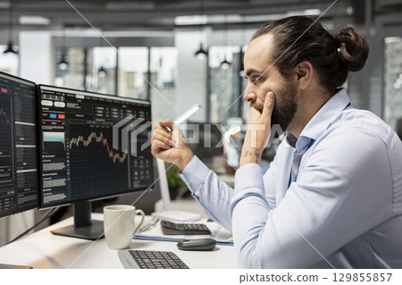 Upset trader in prop firm office feeling dejected after losing money while executing trades using trading app on PC. Stressed man worries about losses while monitoring stock exchange 129855857