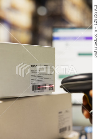 Close up of staff member managing barcodes awb scanning tasks for online shopping orders, products with shipping labels and details for easy delivery. Fulfillment center employee. Close up of staff member managing barcodes awb scanning tasks for online shopping orders, products with shipping labels and details for easy delivery. Fulfillment center employee. 129855912