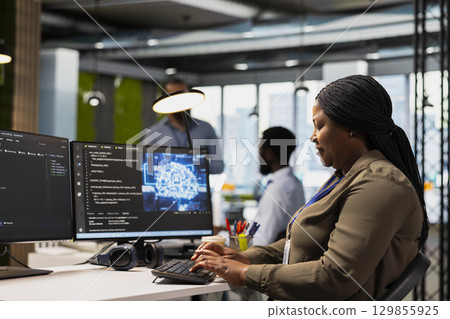 System administrator in office using AI automation scripts to reduce repetitive coding tasks. Woman using artificial intelligence technology on PC in high tech startup workspace 129855925