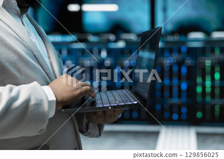 Close up of admin programming in AI data center housing advanced equipment used for machine learning training. Data scientist running code to upgrade artificial intelligence tech 129856025
