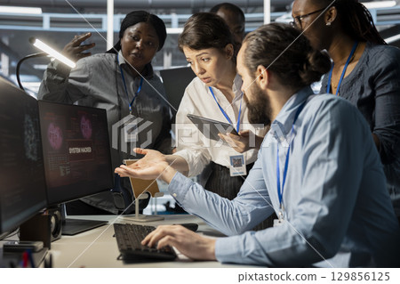 Data center technicians reacting to virus alert on computer monitor, initiating protocol to protect critical systems. Server room teamworking colleagues assessing compromised gear after hacker attack 129856125