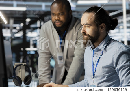 Team of technicians in data center using PC to update storage arrays software, configuring network virtualization. Teamworking colleagues in server room using computer to verify settings 129856129