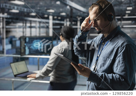 Server hub technicians identifying hardware issues using predictive machine learning alerts, guiding users. Teamworking data center coworkers using headset mic, using AI to resolve clients issues 129856220