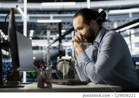 Impatient engineer in data center waiting for storage arrays software to update, configuring network virtualization. Upset man in server room annoyed by unstable system performance Impatient engineer in data center waiting for storage arrays software to update, configuring network virtualization. Upset man in server room annoyed by unstable system performance 129856221