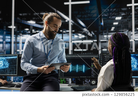 Data center manager and intern adjusting AI model parameters to upgrade systems. Server room IT team leader and trainee scheduling machine learning ran maintenance for hardware components 129856225