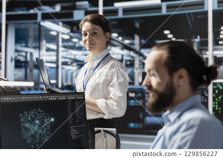 Portrait of smiling data center technician analyzing software logs metrics on laptop, optimizing storage systems. Upbeat server room employee inspecting resource utilization on notebook Portrait of smiling data center technician analyzing software logs metrics on laptop, optimizing storage systems. Upbeat server room employee inspecting resource utilization on notebook 129856227