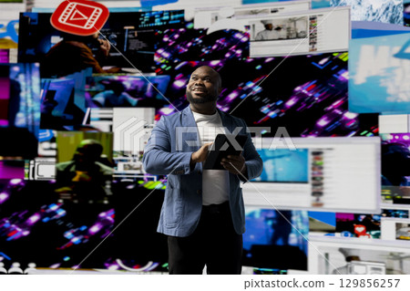 Black young social network user checks dashboards with dynamic screens showcasing social media and networking, highlighting the importance of online engagement and global connection. 129856257