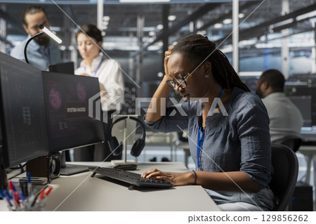 Server farm employee trying to fix compromised equipment after hacker attack. Engineer in data center disturbed by malicious threat alert, initiating protocol to protect critical systems Server farm employee trying to fix compromised equipment after hacker attack. Engineer in data center disturbed by malicious threat alert, initiating protocol to protect critical systems 129856262