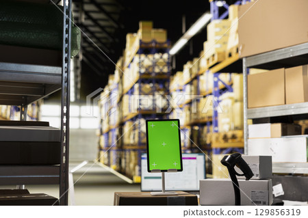 Empty supply room with isolated copy space screen on tablet, ideal for logistics or tracking software or retail e-commerce dashboards. Surrounded by shelves and boxes for order fulfillment. 129856319