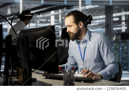 System administrator in data center doing software updates, verifying neural network parameters. Server hub IT expert using PC to inspect configurations, ensuring optimal application performance 129856408