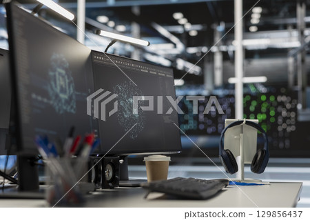 Computer screen in data center office overseeing server cabinets preserving datasets required for artificial intelligence systems. PCs in workspace used for monitoring blade servers infrastructure 129856437