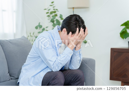A man crouching and holding his head 129856705