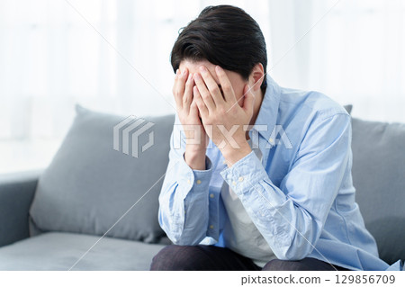 A man crouching and holding his head A man crouching and holding his head 129856709