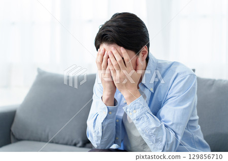 A man crouching and holding his head A man crouching and holding his head 129856710