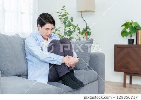 Man crouching on sofa 129856717