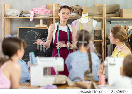 Female sewing teacher explaining garment construction to children 129856984