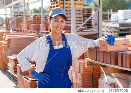 Portrait of female worker at warehouse of building materials in open air 129857008