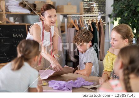 Teacher tells children how to make patterns and learn to sew 129857145