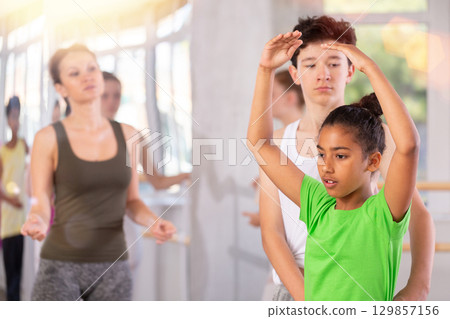 Teenage girl practicing ballet positions in pair with boy in dance studio 129857156
