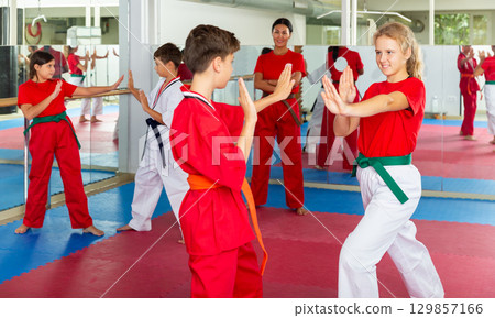 Young positive teenagers practicing new karate moves in pairs in class 129857166