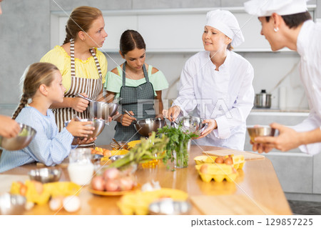 At cooking course, woman cook tells children about rules of cooking fluffy pancakes At cooking course, woman cook tells children about rules of cooking fluffy pancakes 129857225