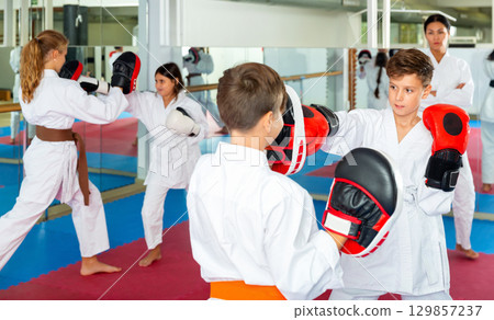 Children practicing boxing punches in pairs Children practicing boxing punches in pairs 129857237