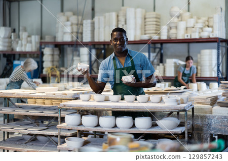 African american artisan having ceramics in hands and standing in workshop 129857243