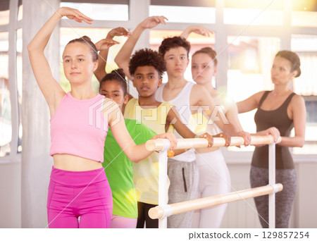 Teen girl learning third ballet position in beginner class 129857254