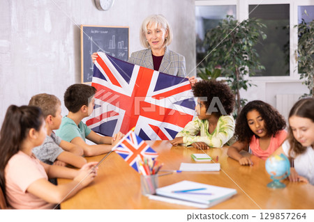 Female teacher showing british flag to kids in geography class Female teacher showing british flag to kids in geography class 129857264
