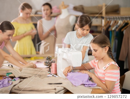 Girl sews on a sewing machine. Boy watches and learns 129857272