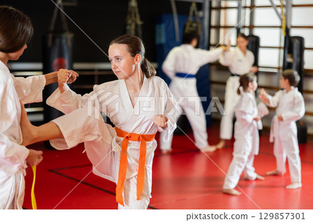 Two teenage girls practice karate in pairs 129857301