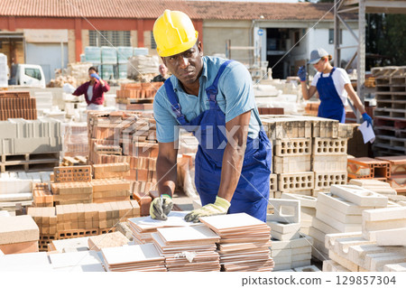 Focused african american man lays tiles in a warehouse 129857304