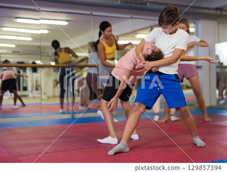 Boys and girls learn together in self-defense lesson to do painful head grab 129857394