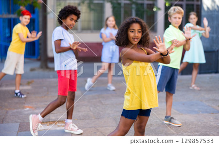 Smiling african american preteen girl dancing with tweenagers on city street Smiling african american preteen girl dancing with tweenagers on city street 129857533