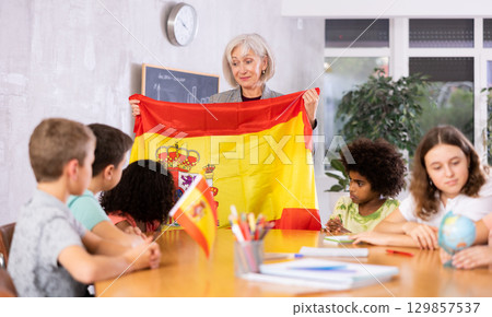 Female teacher showing spanish flag to kids in geography class 129857537