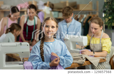 Preteen girl holding fabric during school sewing class 129857568