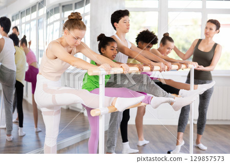 Group of teenage dancers practicing stretching at barre 129857573