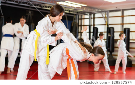 Teen girls athletes in pair conduct training battle in oriental fighting technique Teen girls athletes in pair conduct training battle in oriental fighting technique 129857574