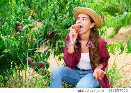 Young lady eating juicy peach Young lady eating juicy peach 129857623