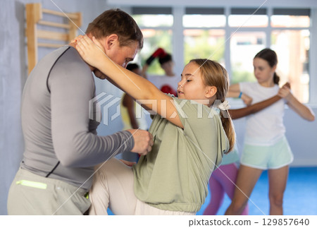 Coach and girl training self-defense techniques 129857640