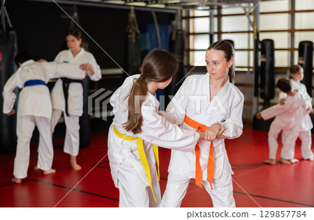 Teenage girls in kimono at judo lesson Teenage girls in kimono at judo lesson 129857784