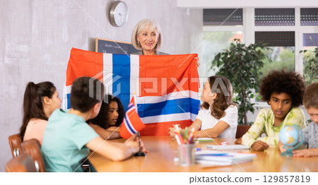 Female teacher showing norwegian flag to kids in geography class Female teacher showing norwegian flag to kids in geography class 129857819