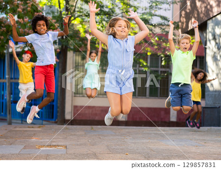 Happy tween girl jumping with friends on city street 129857831