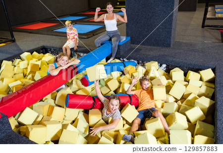 Company of joyful smiling kids playing and lying among soft cubes at childrens amusement park Company of joyful smiling kids playing and lying among soft cubes at childrens amusement park 129857883