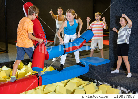 Teen girl having fun on battle beam with preteen brother Teen girl having fun on battle beam with preteen brother 129857898