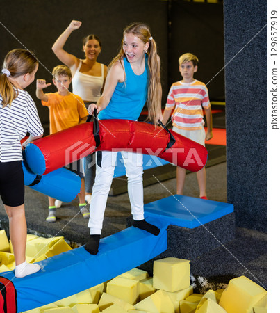 Teen girl doing funny fighting on battle beam with preteen girl 129857919